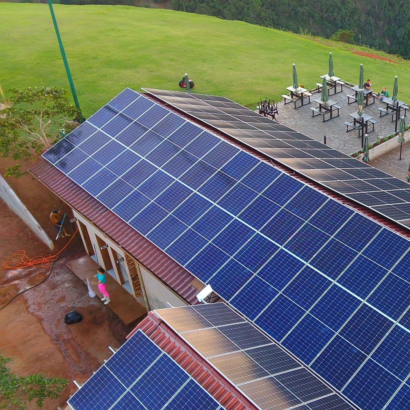 Painéis solares em cobertura de imóvel comercial, com área externa e gramado ao fundo