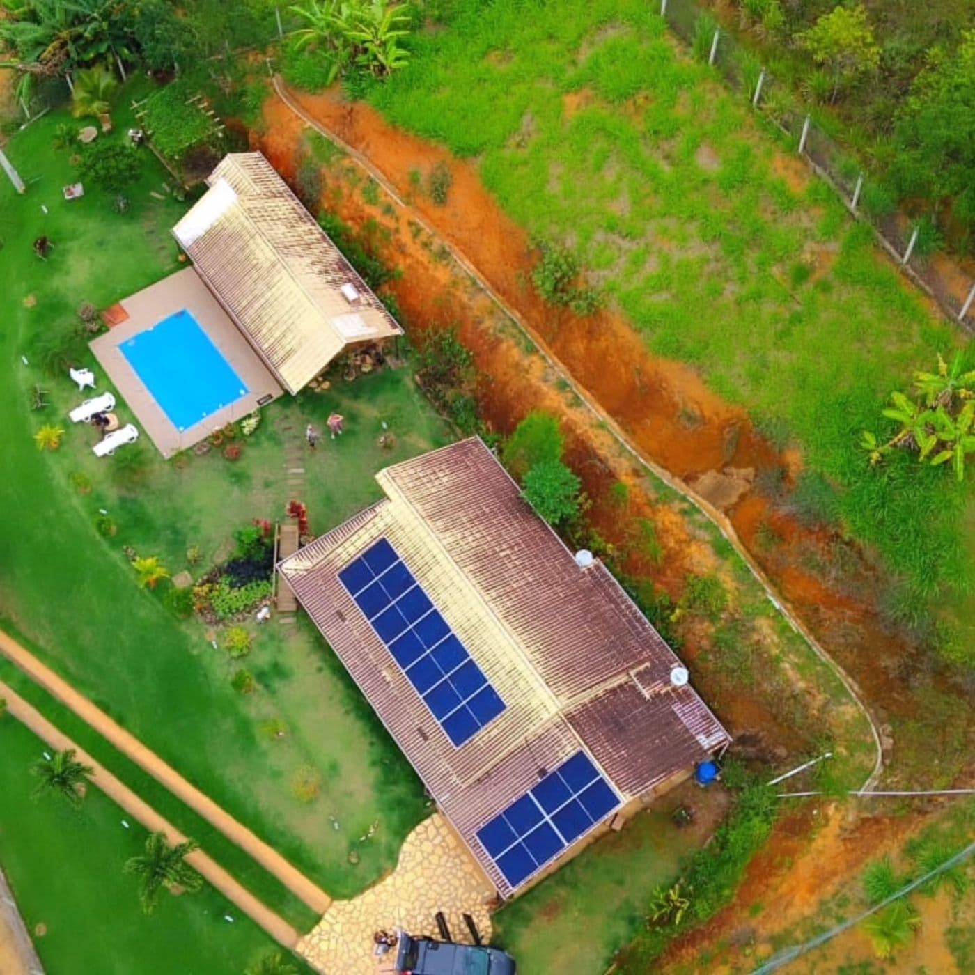 Vista aérea de residência com piscina e painéis solares em dois lados do telhado